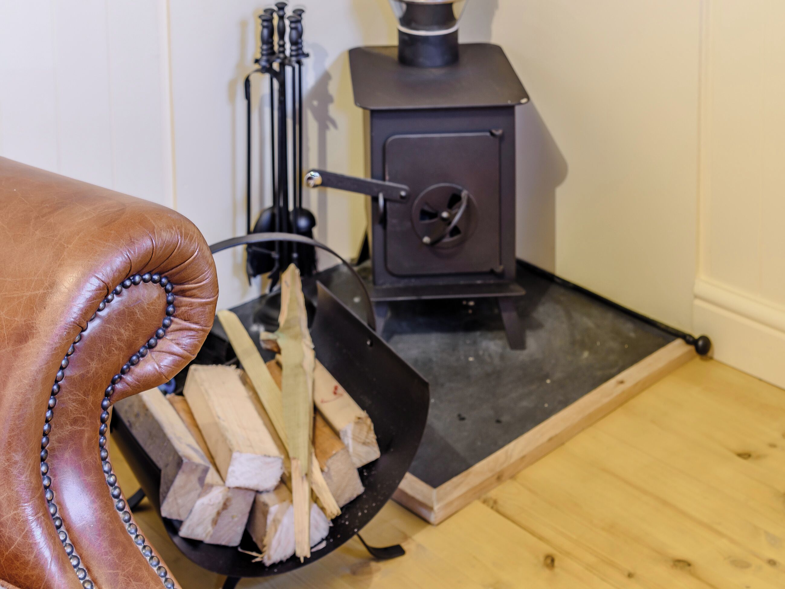 A fireplace with logs and a black metal stand.