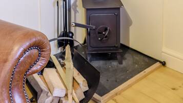 A fireplace with logs and a black metal stand.