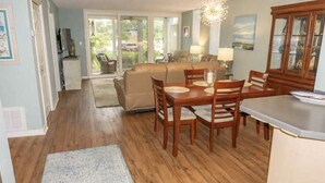 Un espace repas comprenant une table et des chaises en bois, un canapé et un coin cuisine avec un plan de travail et des placards.
