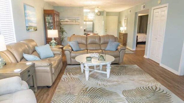 Un salon avec un ensemble de canapés de couleur beige, une table basse et un tapis à motifs.