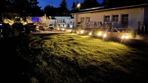 Un espace extérieur bien éclairé, comprenant une pelouse, un coin salon et un bâtiment doté de nombreuses fenêtres.