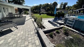 Une terrasse avec mobilier d’extérieur, une piscine et un jardin.