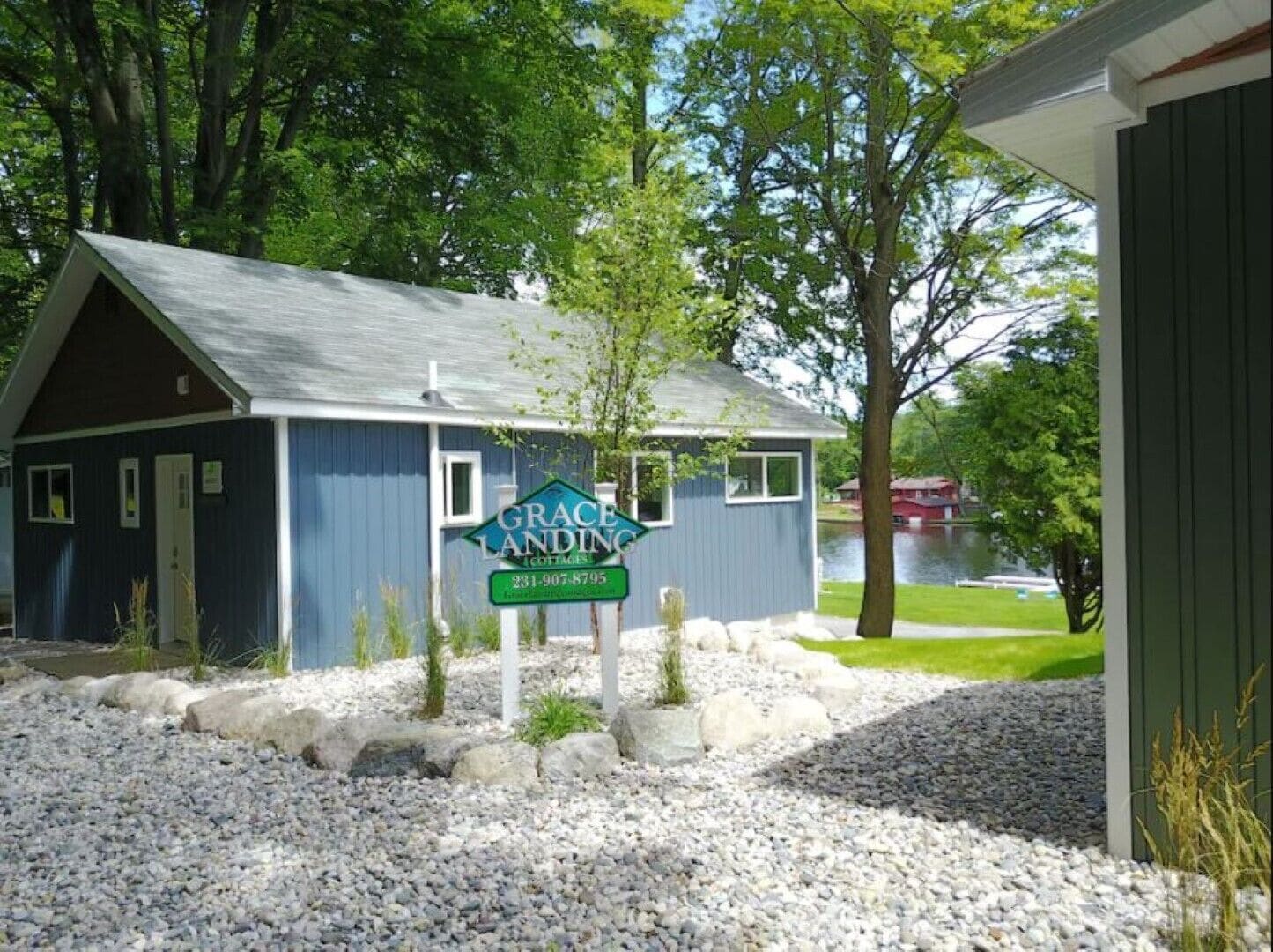 A small cottage with a blue exterior and a sign that reads "Grace Landing Cottages."