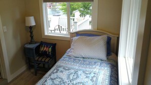 Un dormitorio con una cama, un ventanal con vistas al exterior, una silla y una lámpara.