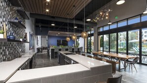 Eine moderne Küche und Essbereich mit einer langen Theke, einer Bar und großen Fenstern mit Blick ins Freie.