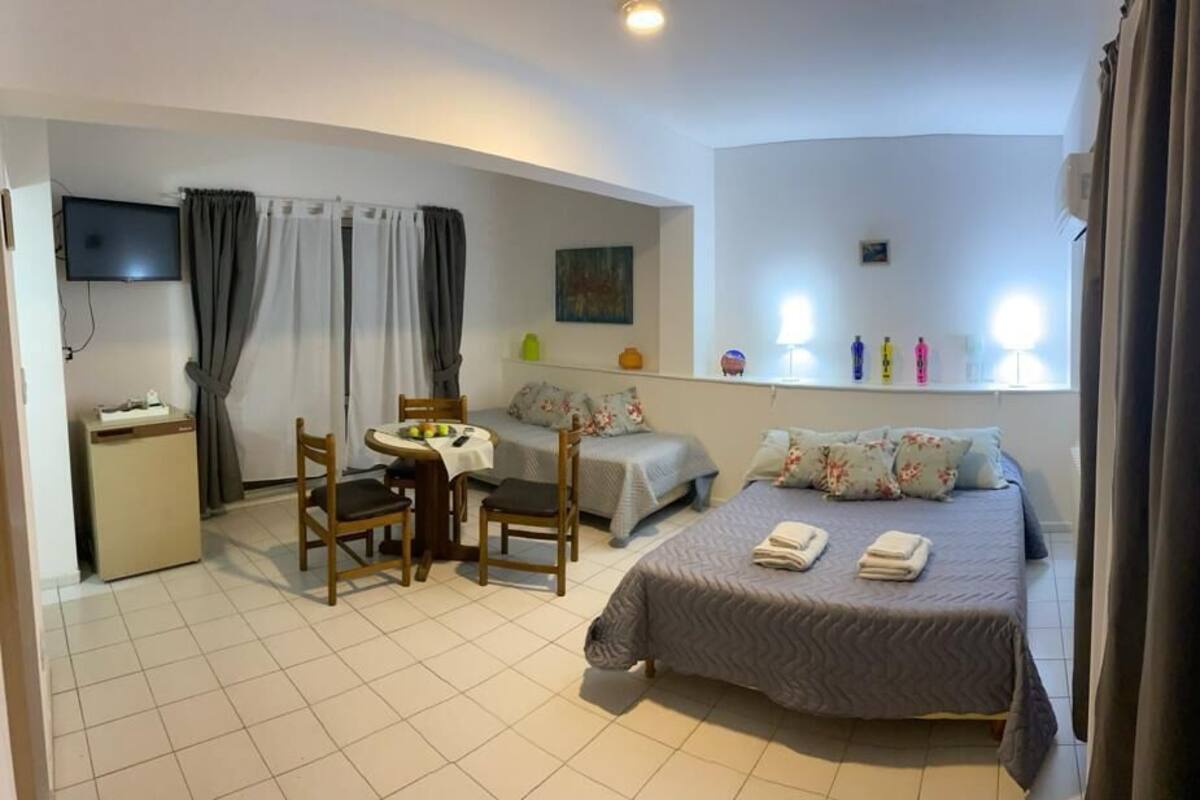 A hotel room with a bed, a desk, a chair, and a small table.
