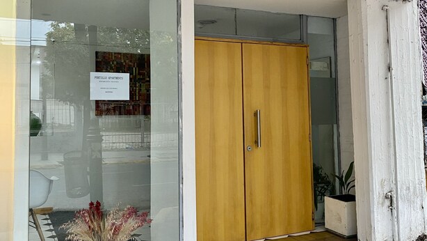 A building entrance with a glass door, a wooden wardrobe, and a sign indicating 'PORTILLO APARTMENTS'. - Portillo Apartments (Mendoza)
