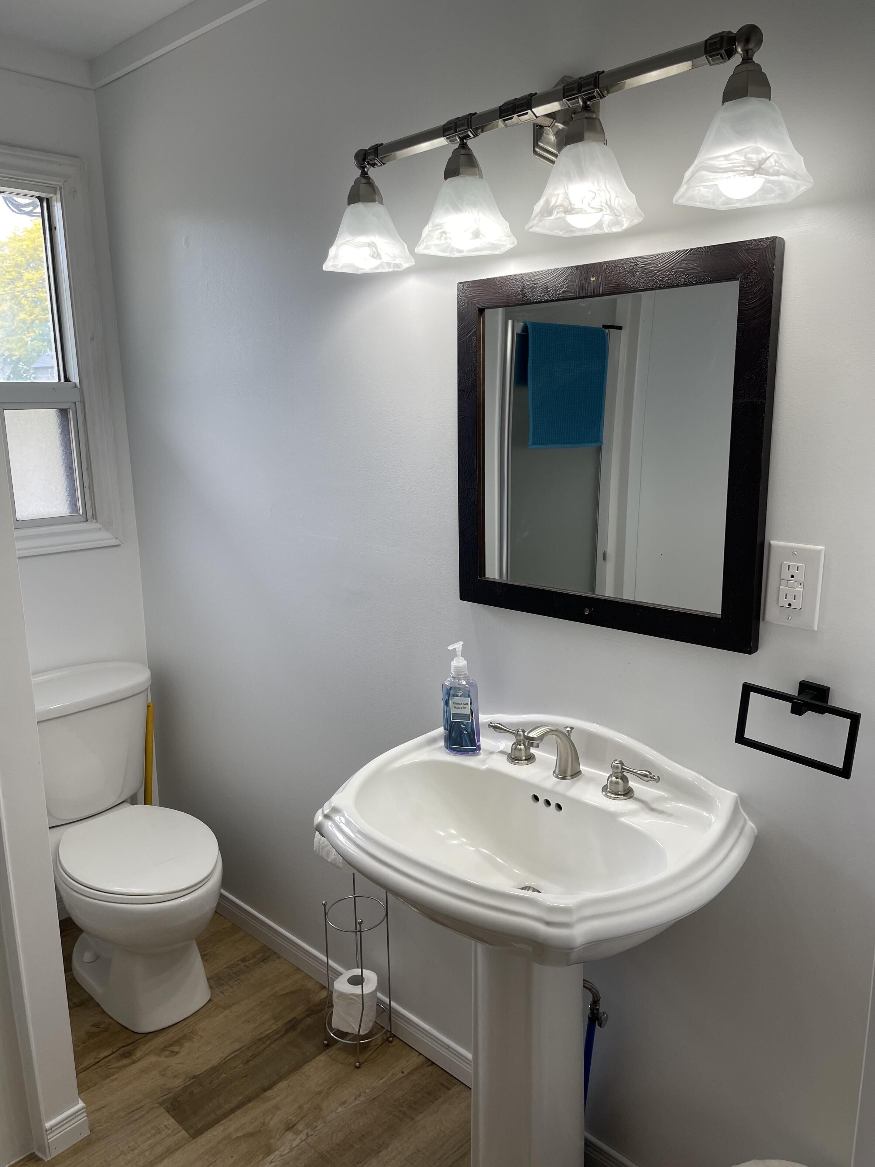 Un bagno con lavandino bianco, uno specchio e un water.