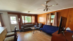 Un salon confortable avec un canapé, des fauteuils, une table basse et un téléviseur.