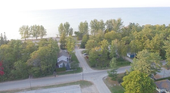 An aerial view of a residential area with houses, a road, and a body of water in the background.