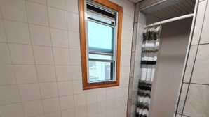 Un baño con inodoro, lavamanos, ventana y cortina de ducha.