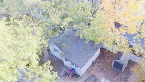 An aerial view of a house with a fenced yard, a small shed, and a fire pit area.