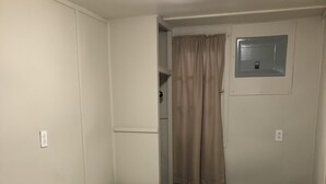 A small, compact room with a single bed, a small window with a curtain, and a door with a lock. - Dock Life Cottage 10 - Riverside, 2 Bedroom, Wasaga (Wasaga Beach)