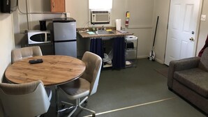 A compact kitchen with a microwave, refrigerator, and sink. There is a dining table with chairs and a sofa. - Dock Life Cottage 10 - Riverside, 2 Bedroom, Wasaga (Wasaga Beach)