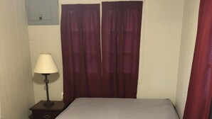 Tyypillinen hotellihuone, jossa on sänky, yöpöytä, lamppu ja ikkuna, jossa on verhot.