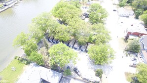 Ett flygbildsbild av ett bostadsområde med hus, en flod och parkerade bilar.