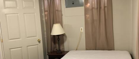 A room with a bed, a desk, a lamp, and curtains.