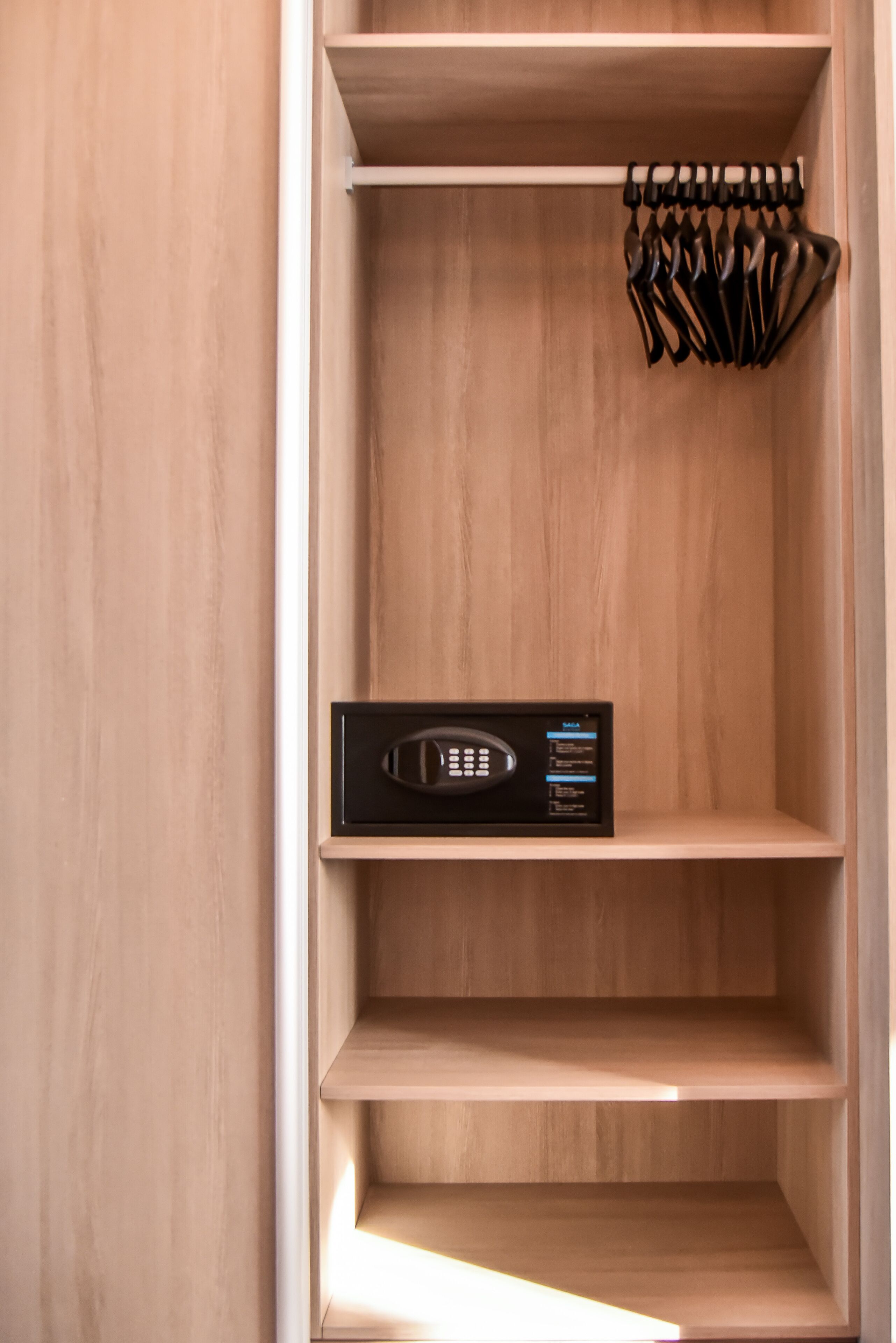 A wooden closet with multiple shelves and a hanging rack.