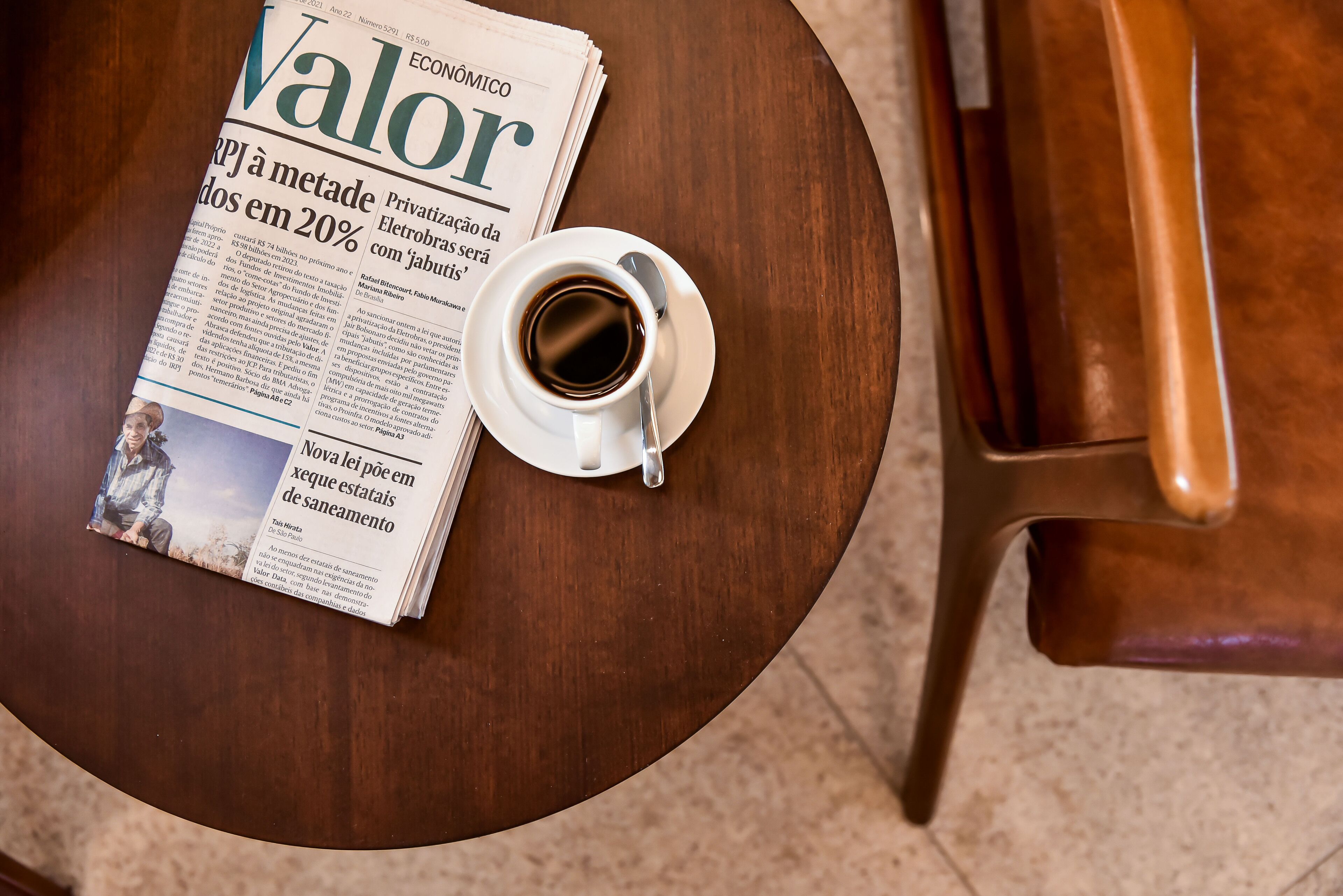 Een krant met de titel 'Valor' op een ronde houten tafel, met een koffiekop ernaast.