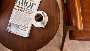 Een krant met de titel 'Valor' op een ronde houten tafel, met een koffiekop ernaast.