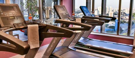 A gym with treadmills, a water bottle, and a TV on the wall.