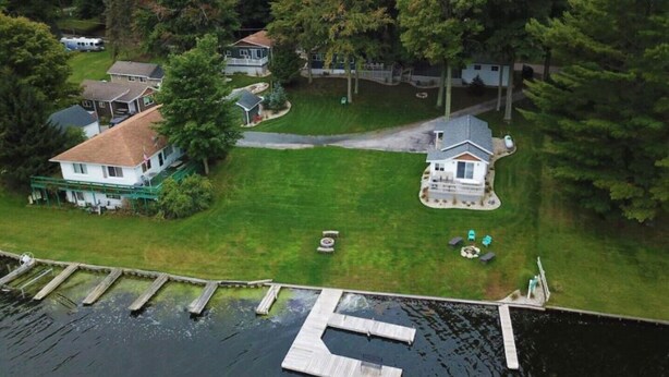 A lakeside property with multiple houses, a dock, and a well-maintained lawn.