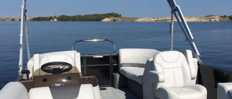 Un barco con toldo, asientos de cuero blanco y timón.