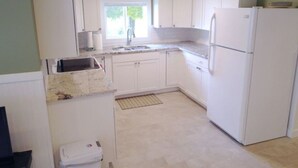 A compact kitchen with white cabinets, a sink, and a refrigerator.