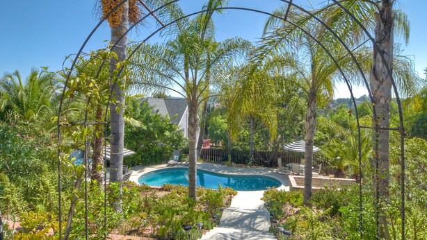 A swimming pool surrounded by lush greenery and palm trees. - Two Homes, One
 Lot Sleeps 18, Pool & Hot Tub Private Villa, 9 miles from beach. (Vista)
