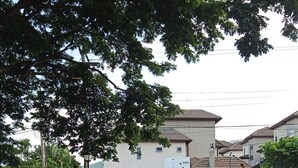 Zona residencial cerrada con camino pavimentado, un coche aparcado y un edificio con tejado de tejas.
