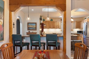 A dining area with a wooden table, three chairs, and a hanging light fixture. - Sunlit Pines - Tucked in the Trees, Private Escape, Easy Drive to Plaza - NEW Listing (Santa Fe)