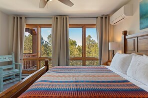 A bedroom with a bed, a nightstand, a lamp, a window with curtains, and a view of trees. - Sunlit Pines - Tucked in the Trees, Private Escape, Easy Drive to Plaza - NEW Listing (Santa Fe)