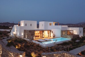 Une villa moderne dotée d’une piscine, de murs en pierre et offrant une vue sur le paysage.