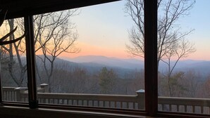 Quarto com uma grande janela com vista para uma paisagem montanhosa.