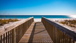 A wooden boardwalk leading to a beach with clear blue water. - Directly on the Ocean! Beautiful Views! Free Beach Chairs and Umbrella sleeps 6 (Pensacola Beach)