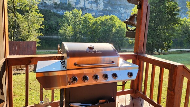 A NexGrill barbecue grill on a wooden deck with a view of a rocky cliff and trees.