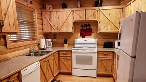 A compact kitchen with wooden cabinets, a white stove, a dishwasher, and a refrigerator.