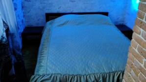 A bedroom with a bed, a nightstand, and a brick wall. - Cozy guest house near Braslaw lakes (Braslaw)