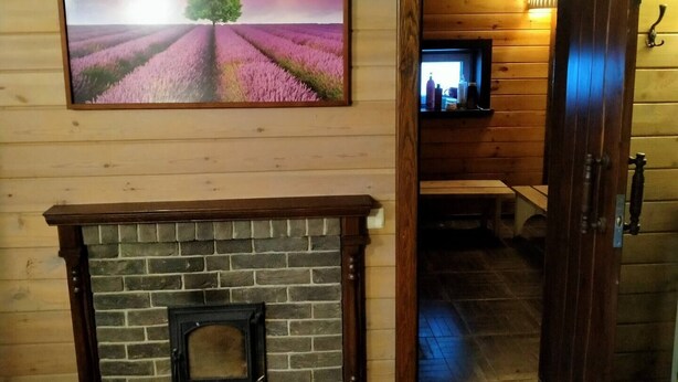 A wooden interior with a fireplace, a painting of a lavender field, and a television on a shelf. - Cozy guest house near Braslaw lakes (Braslaw)