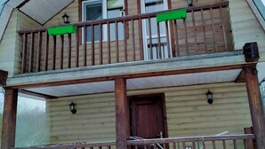 A two-story wooden house with a balcony, a front door, and two windows. - Cozy guest house near Braslaw lakes (Braslaw)