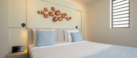Una habitación de hotel moderna con una cama grande, una mesita de noche con lámpara y una lámpara de pared.