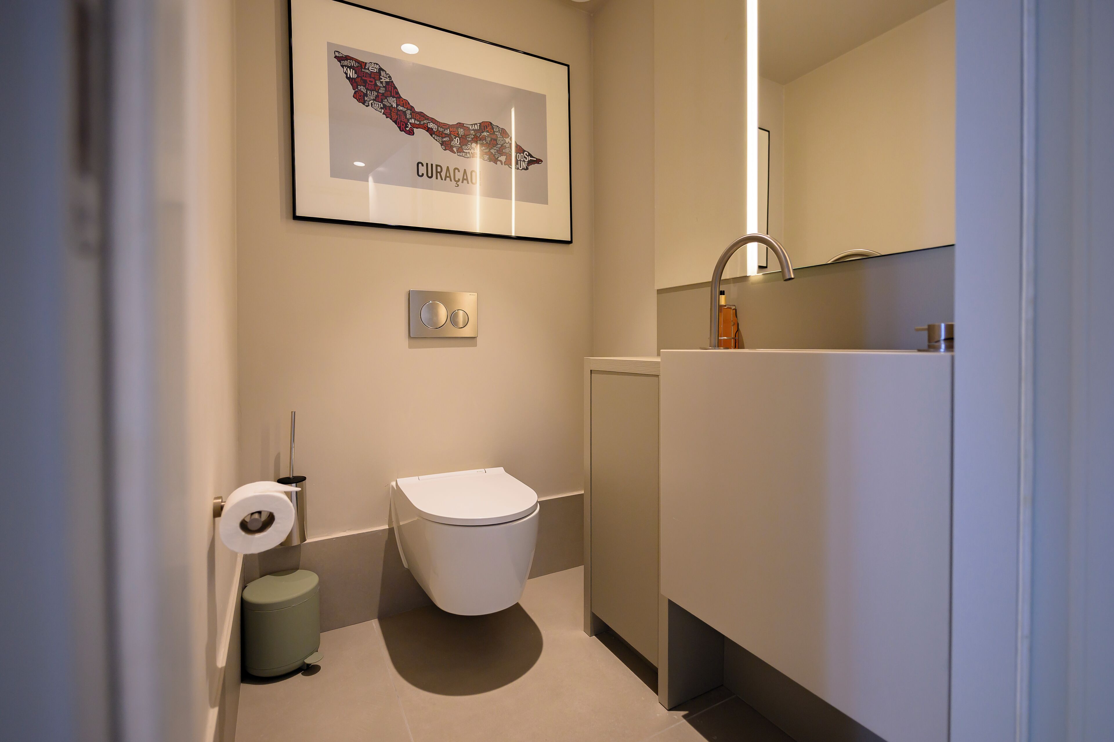 Un baño moderno con inodoro, lavamanos y un mapa enmarcado en la pared.