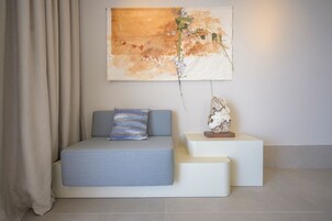 Una habitación moderna con sofá, una mesita y un cuadro abstracto colgado en la pared.