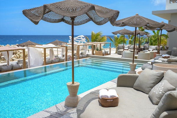Una piscina al aire libre, camas de piscina con cargo, sombrillas