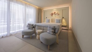 Ein modernes Hotelzimmer mit einem großen Bett, zwei Sesseln, einem kleinen runden Tisch und einer dekorativen Wanddekoration.