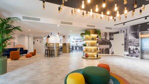 Een moderne lobby met een centraal zitgedeelte, een bar en een muurschildering.