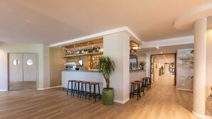 Een ruime hotel lobby met een receptiebalie, bar en diverse zithoeken.