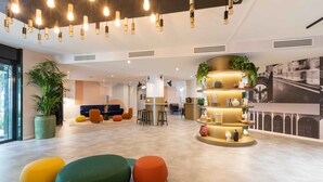 Een moderne lobby met een centrale zithoek, een receptiebalie en een groot raam.