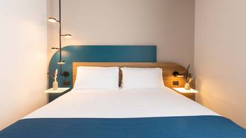 Ein modernes Hotelzimmer mit einem großen Bett, zwei Nachttischen und einer blauen Akzentwand.