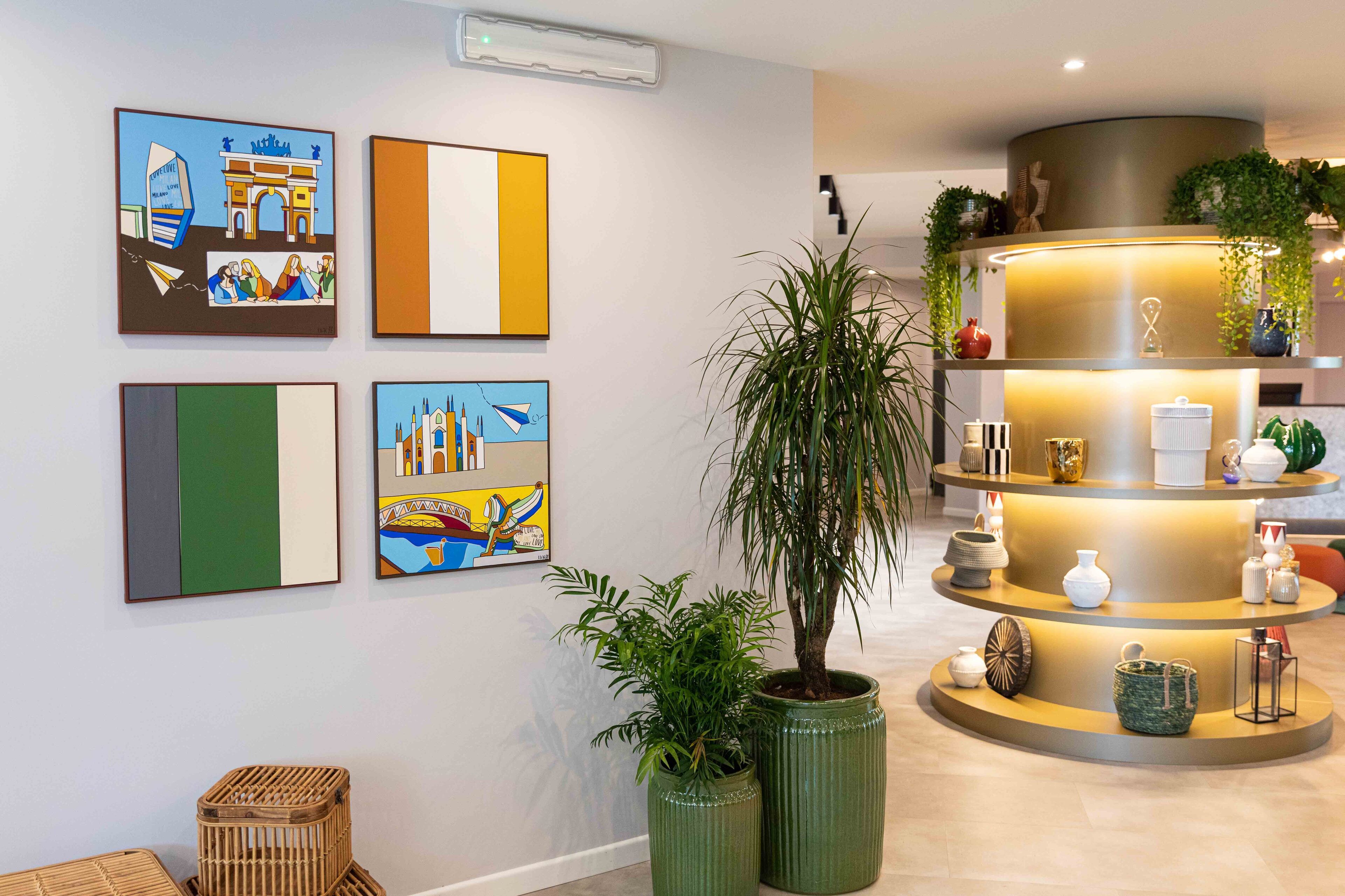 A modern lobby with artwork on the walls, a central plant, and a multi-tiered display shelf with decorative items.